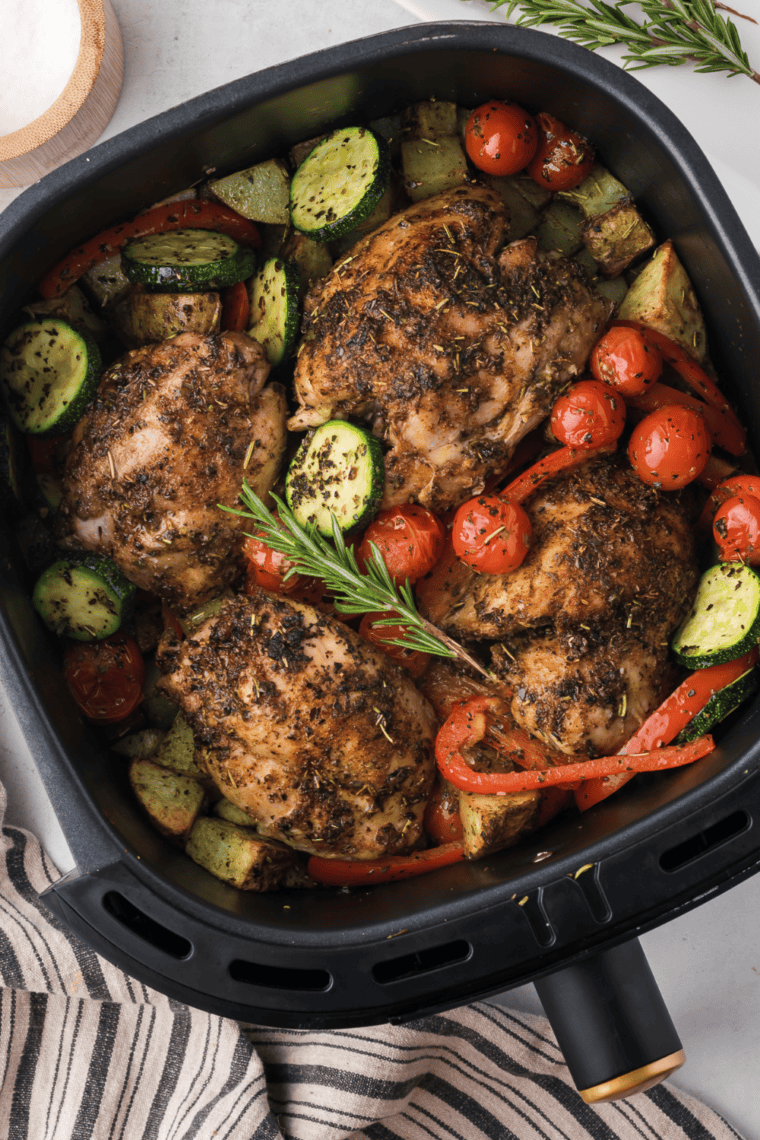 Golden-brown Tuscan chicken thighs cooked in the air fryer, topped with creamy sun-dried tomato and herb sauce.