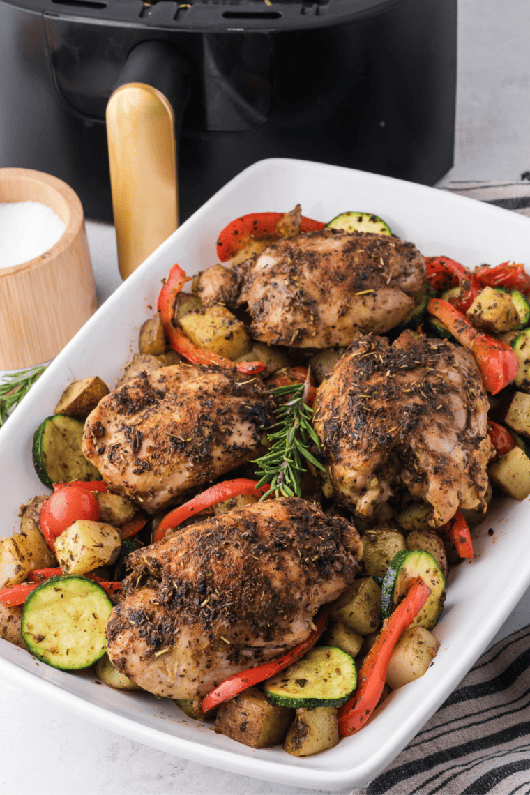 Air-fried Tuscan chicken thighs with golden edges, topped with sun-dried tomatoes and herbs on a serving plate.
