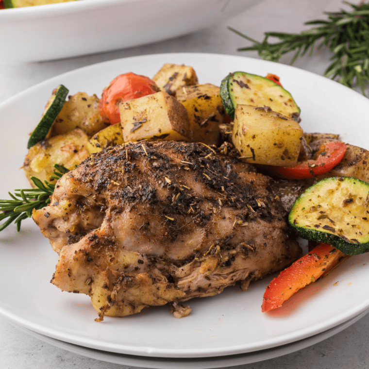 Golden air-fried Tuscan chicken thighs served with crispy potatoes and colorful roasted veggies, all seasoned with herbs and garlic.