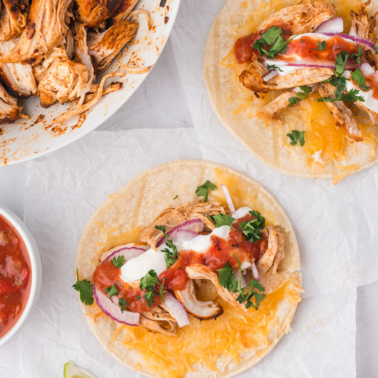 mojo chicken tacos on Blackstone griddle with chopped grilled chicken, lime wedges, and onions