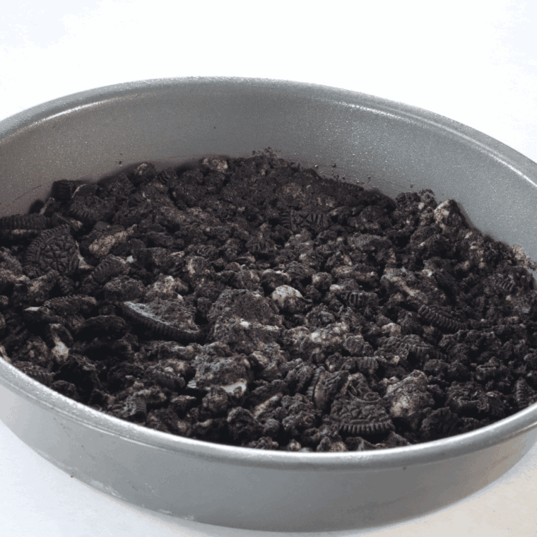 Pressing Oreo cookie crumb crust into a springform pan base.