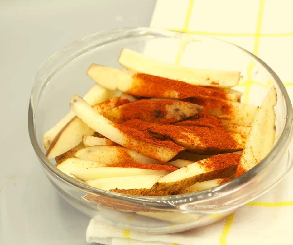Coat the Fries: Place the cut potato fries in a large bowl. Drizzle the olive oil over them and toss to coat evenly. Sprinkle the spicy chili seasoning mix over the fries and toss again until they are well coated with the seasoning.