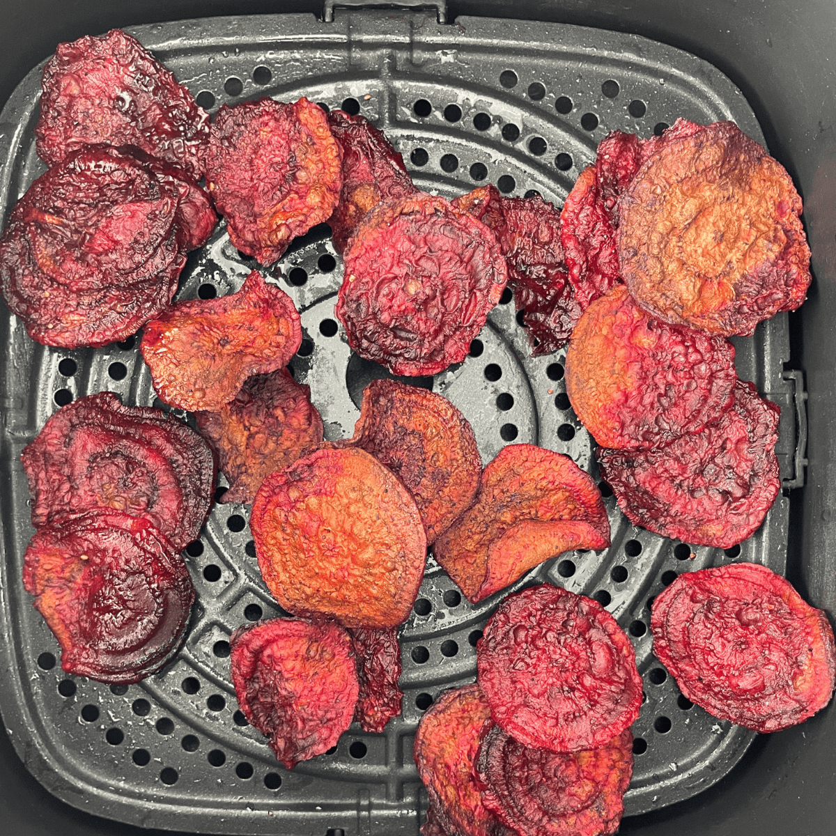 Crispy, golden air fryer beet chips in an air fryer basket.