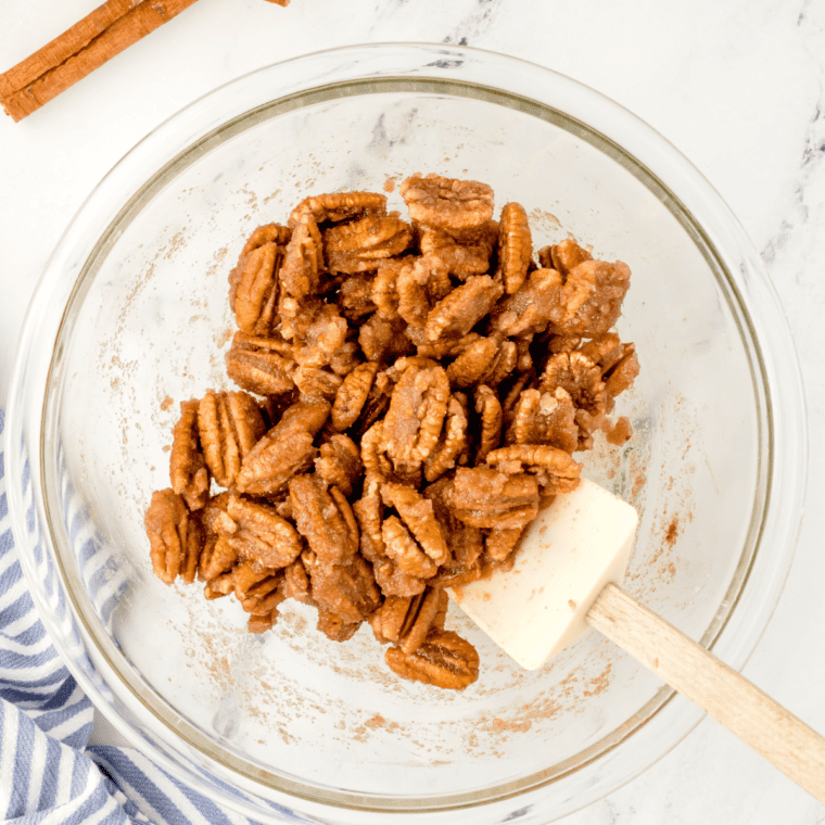 overhead process shot: pecans, sugar, and cinnamon in a large glass bowl after mixing