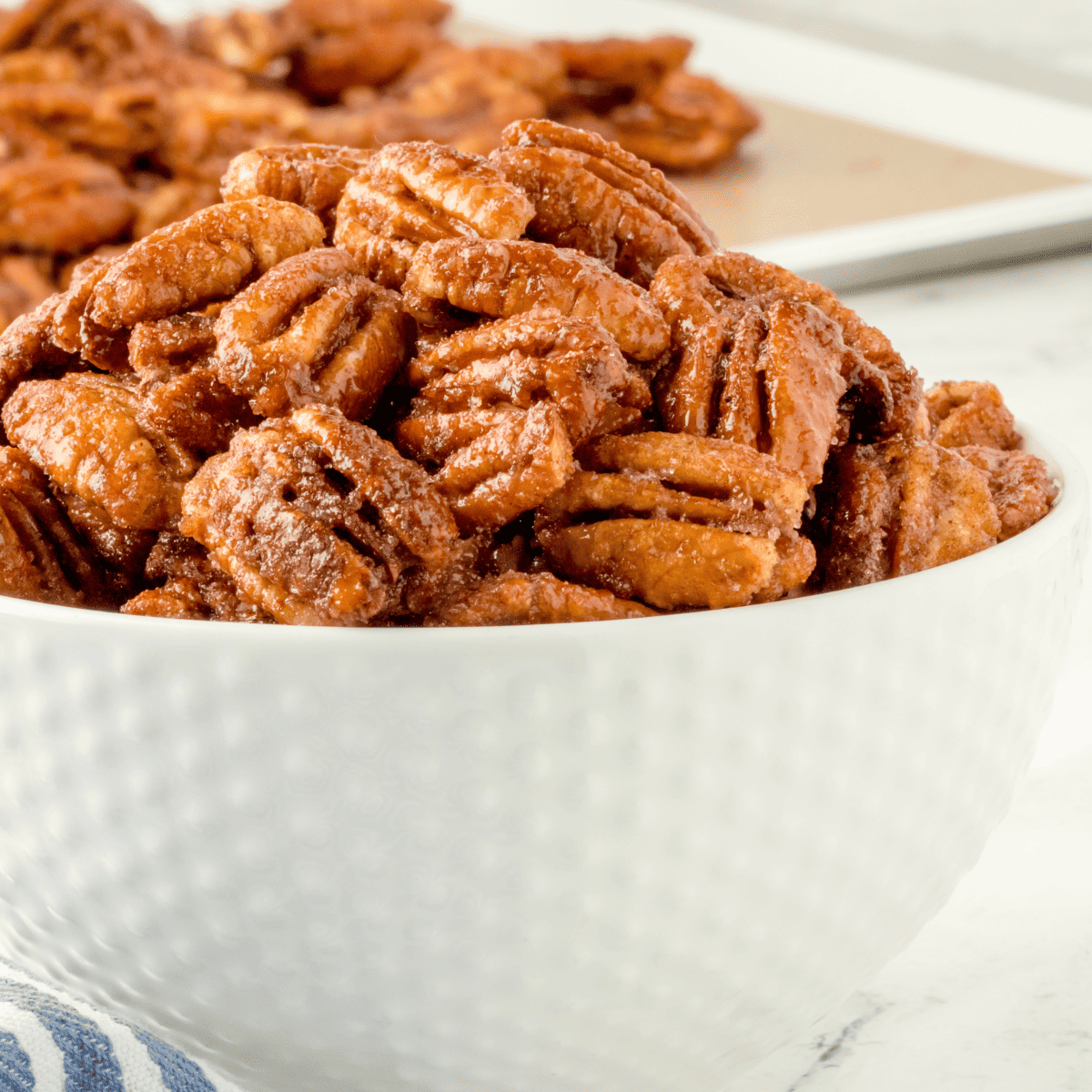 closeup side view: a white bowl full of air fryer candied pecans