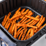 A plate of crispy, golden Air Fryer Carrot Fries, seasoned to perfection and served with a side of dipping sauce.