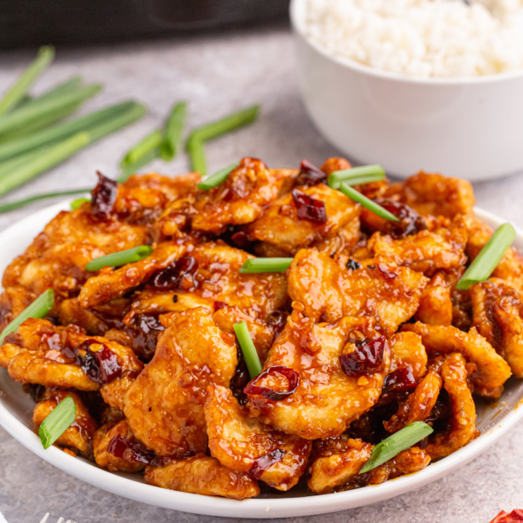 A plate of Air Fryer Mongolian Chicken garnished with green onions and sesame seeds, served alongside steamed white rice.