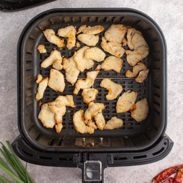 Air fryer preheated to 350°F (175°C), with chicken slices arranged in a single layer, cooking for 8-10 minutes until reaching 165°F (74°C).