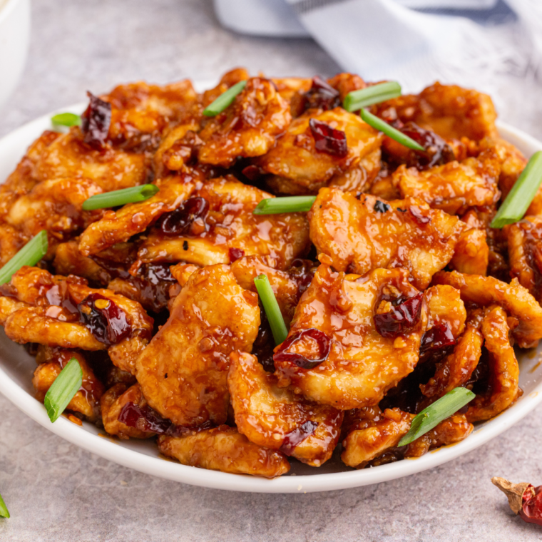 Air Fryer Mongolian Chicken served on a plate with a rich, glossy sauce, garnished with sesame seeds and green onions.