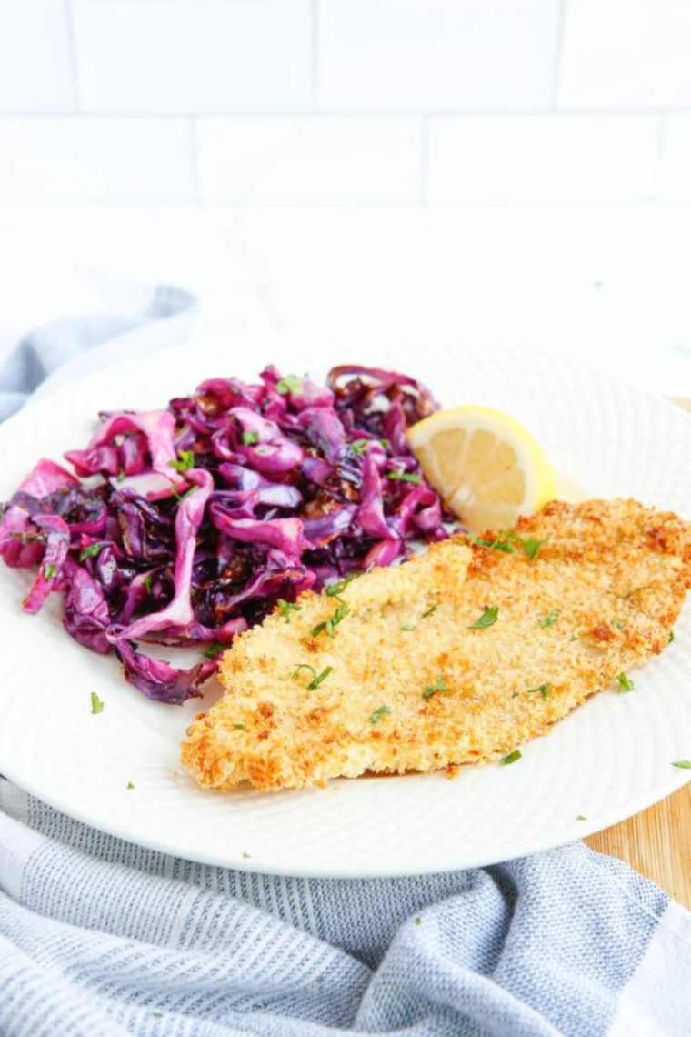 Red cabbage and chicken breast served together on a white plate, showcasing a colorful and healthy meal.