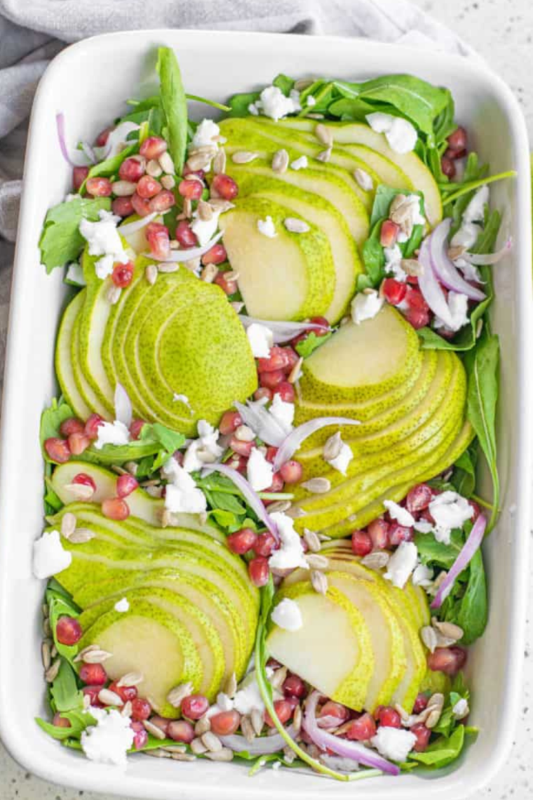 Plate of vibrant Air Fryer Roasted Pear Salad with caramelized pears, mixed greens, pomegranate seeds, crumbled feta, red onion, and sunflower seeds, drizzled with a light vinaigrette