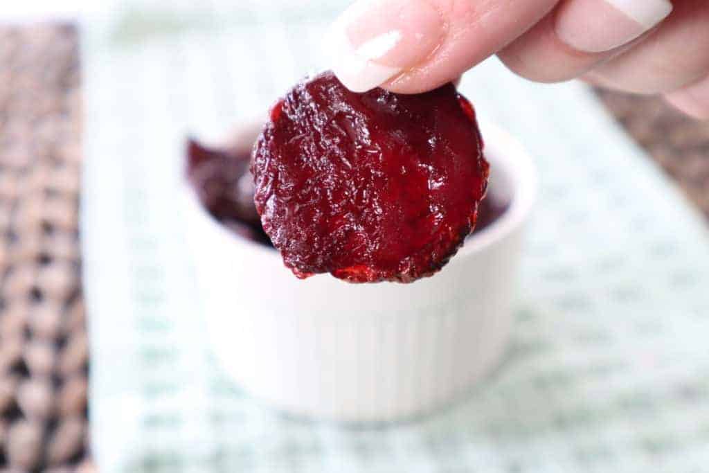 closeup: a hand holding a beet chip made in air fryer