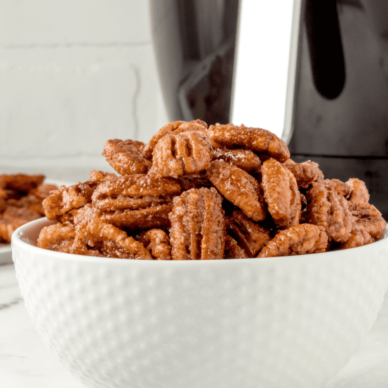 side view closeup: a white bowl full of air fryer candied pecans