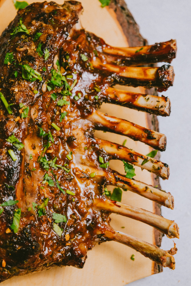 Close-up of lamb chops searing on Blackstone griddle with garlic butter bubbling.