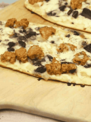 Blackstone griddle cooking a sausage and mushroom flatbread pizza with crispy crust and melted cheese.