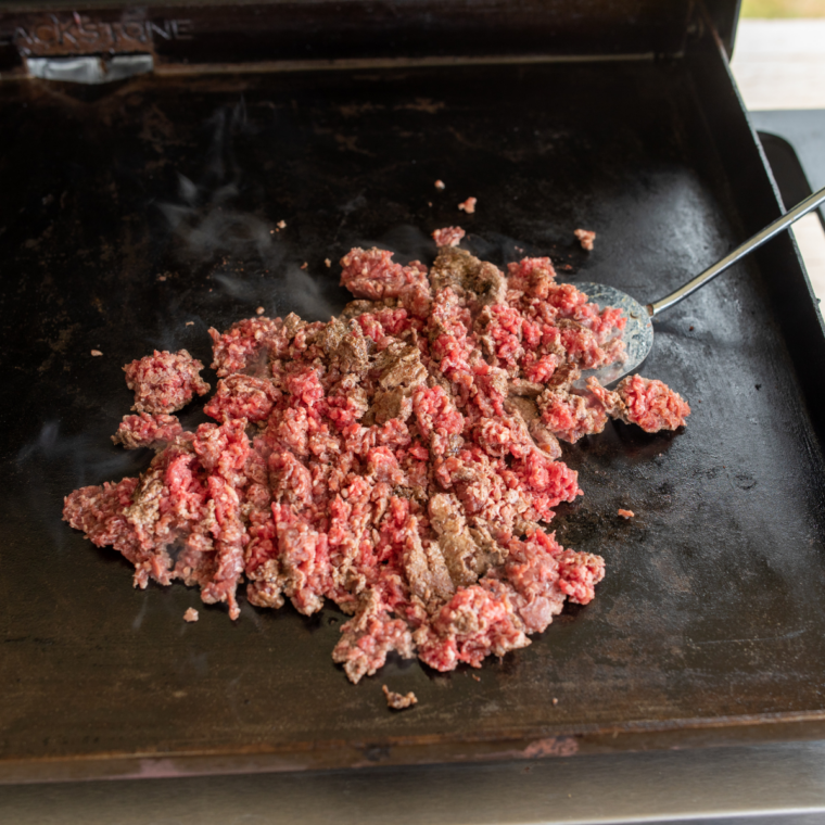 &ndash; Cook the meat:
Ground beef browning with taco seasoning on a Blackstone griddle