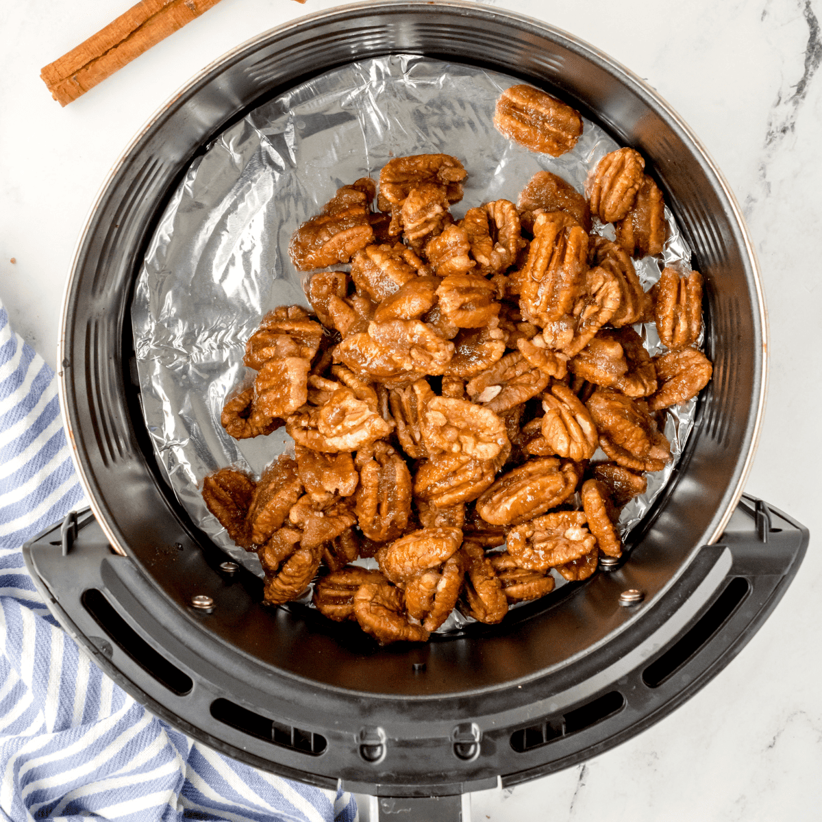 overhead process shot: candied pecans in air fryer basket after air frying