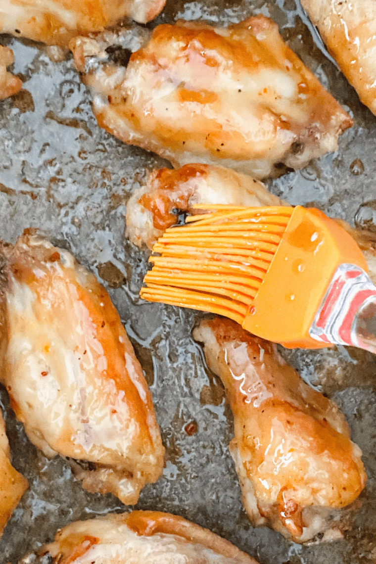 Close-up of golden, crispy chicken wings tossed in Hawaiian-style sauce, plated and garnished for serving.