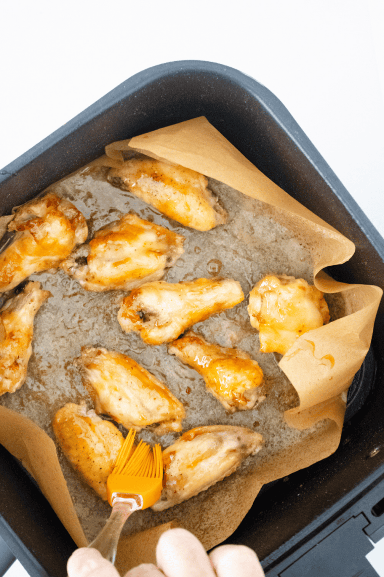 Tossing cooked wings in sweet and tangy Hawaiian sauce until fully coated