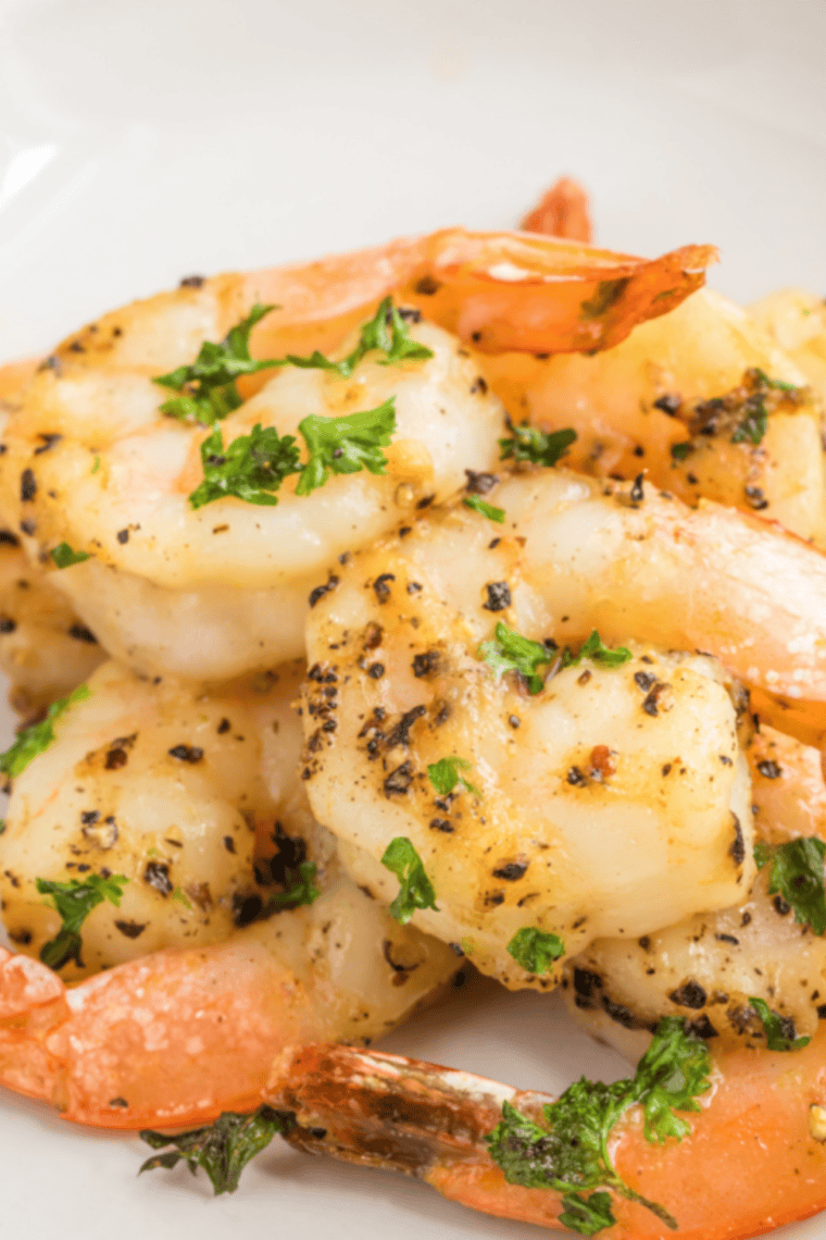Crispy lemon pepper shrimp served on a plate with lemon wedges and garnished with herbs.