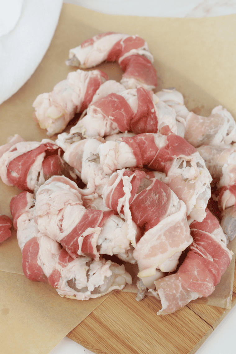 Wrap the Shrimp with Bacon: Raw shrimp wrapped in bacon, secured with toothpicks.