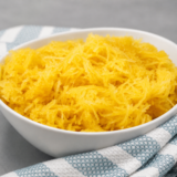 Shredded Ninja Foodi spaghetti squash strands in a white bowl with a fork