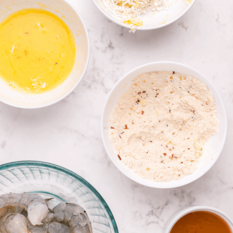 Three bowls set up for breading—flour, beaten eggs, and a mix of panko breadcrumbs and shredded coconut.