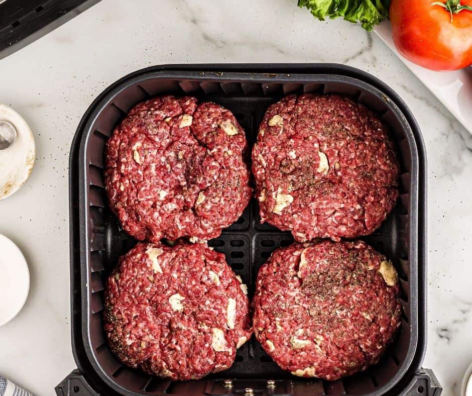 Top view of four raw patties in an air fryer. 