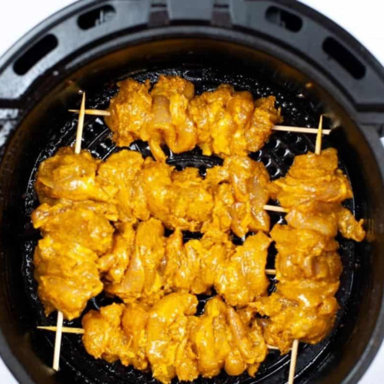 Skewering marinated chicken pieces
Placing skewered chicken in the air fryer basket