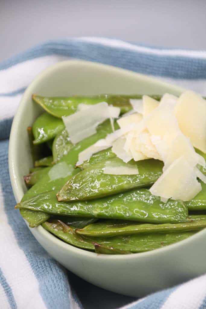 closeup: air fried snap peas in a white bowl with parmesan on top