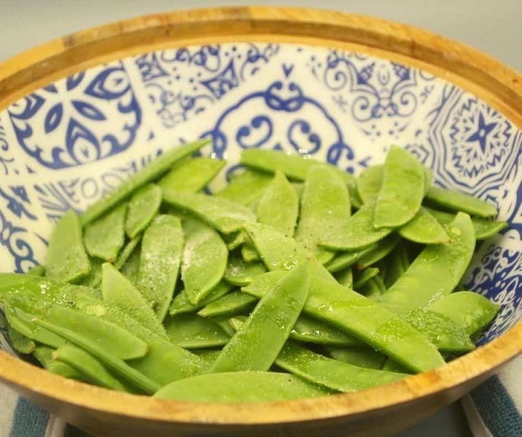 closeup: seasoning snap peas before air frying