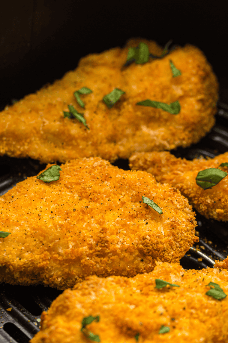 A golden, crispy plate of Air Fryer Chicken Cutlets served with a side of vegetables.