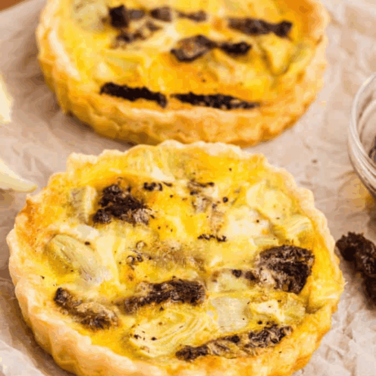 Cooked frozen quiche in air fryer basket with golden crust