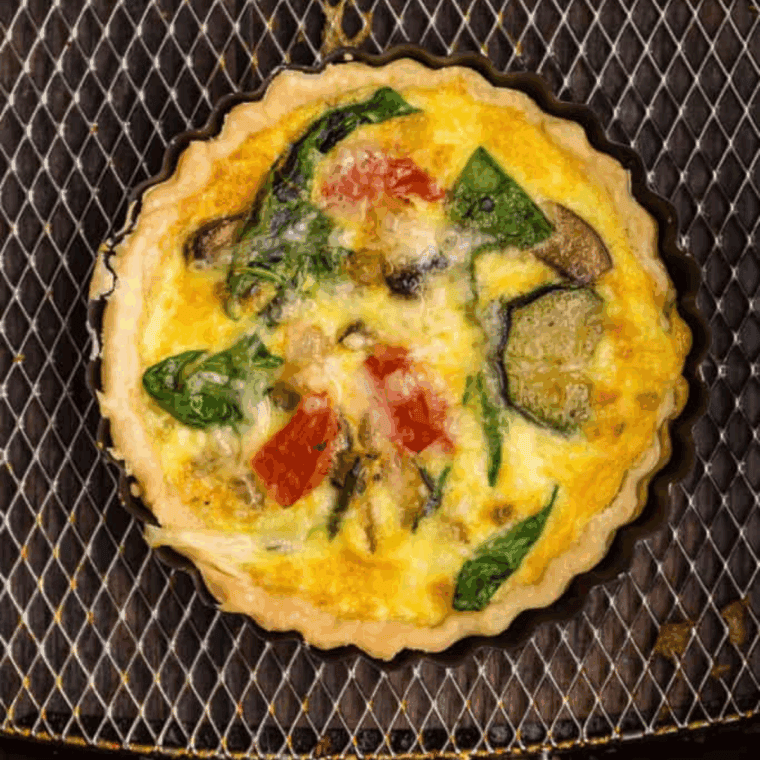 Golden frozen quiche cooked in air fryer basket, ready to serve