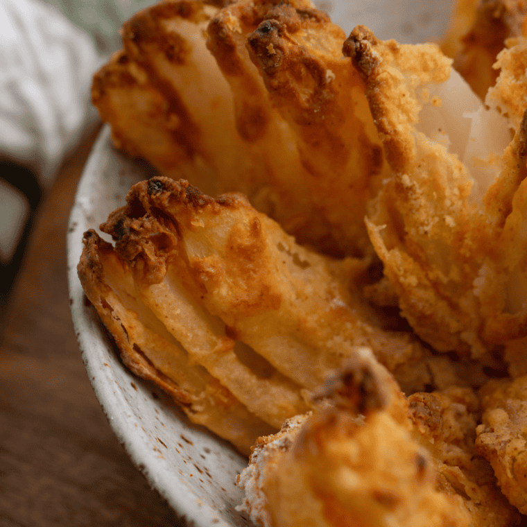 Crispy gluten-free blooming onion cooked in an air fryer, served with dipping sauce on the side