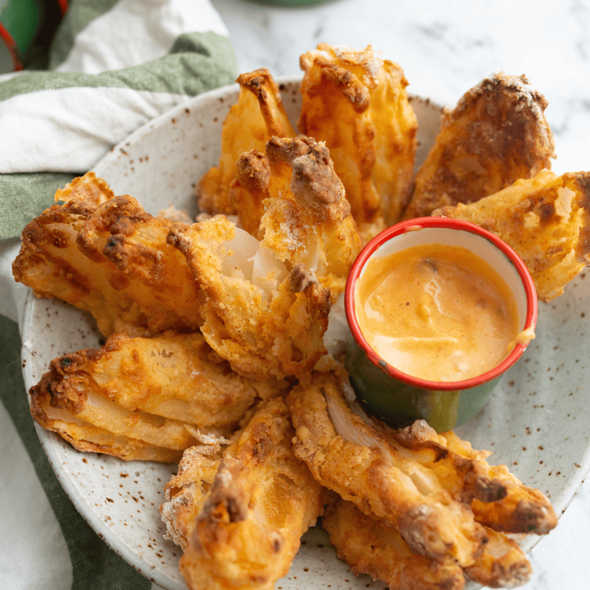 Crispy golden gluten-free blooming onion cooked in the air fryer, served with a creamy dipping sauce