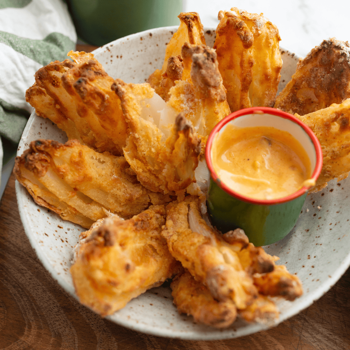 Golden brown air fryer gluten-free blooming onion with crispy seasoned coating, served with dipping sauce
