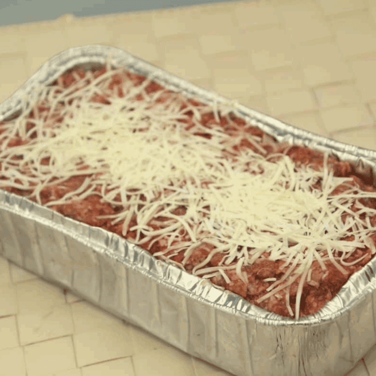 Meatloaf mixture in loaf pan topped with marinara and mozzarella, ready for air frying at 350°F.