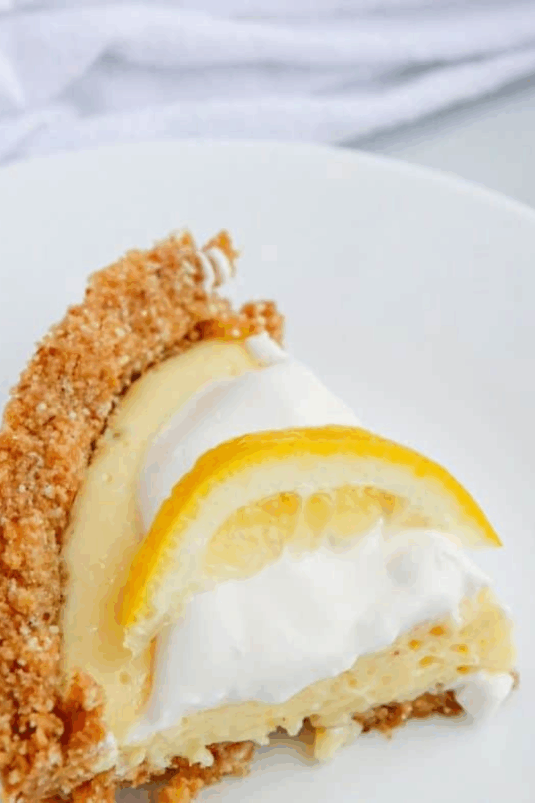 Air fryer lemon pie with golden graham cracker crust, creamy lemon filling, and whipped cream topping garnished with a lemon slice.