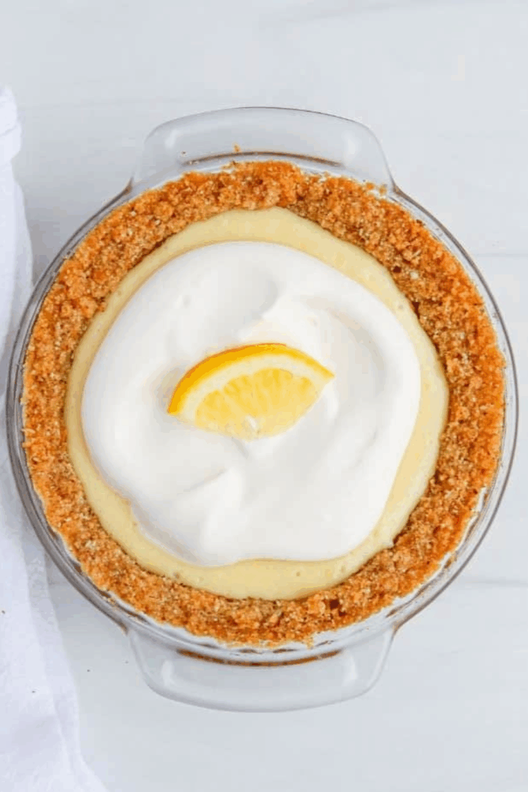 Air fryer lemon pie with golden crust, creamy lemon filling, and whipped cream topping, garnished with a lemon slice.