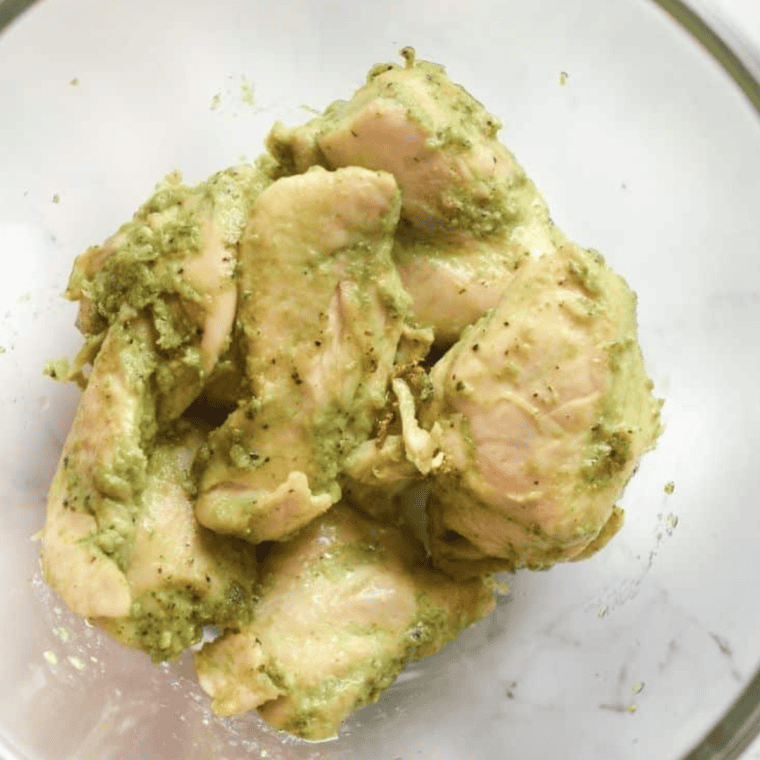 Pesto-coated chicken tenders placed in the air fryer basket, set to 370°F, ready to cook until golden and fully done.