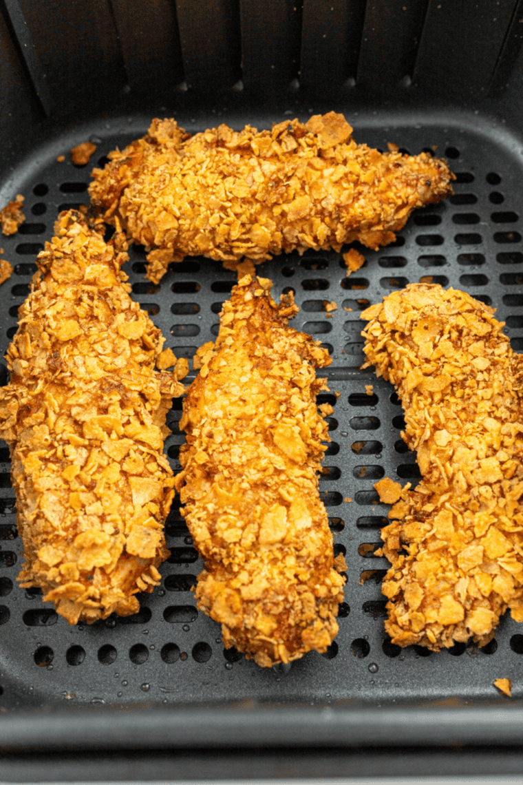 Crispy golden chicken tenders cooked in air fryer, marinated in pickle brine, served on plate with dipping sauce.