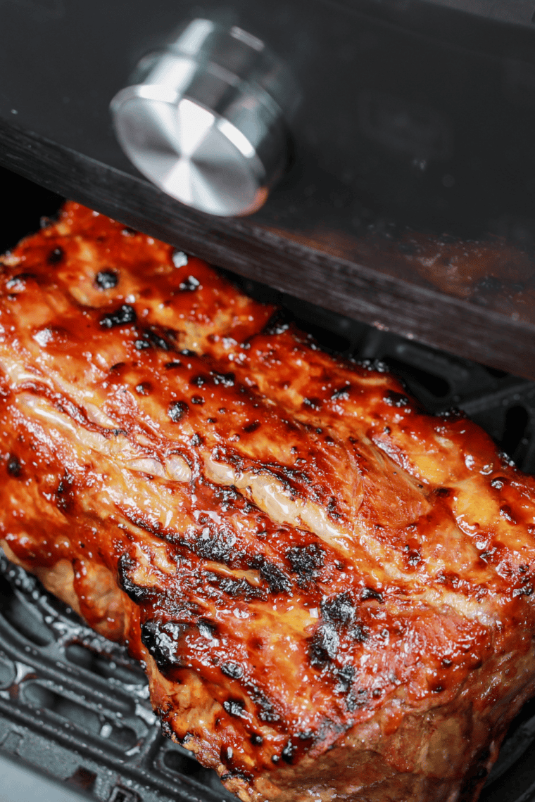 Golden-brown St. Louis style ribs served hot on a plate with sides.