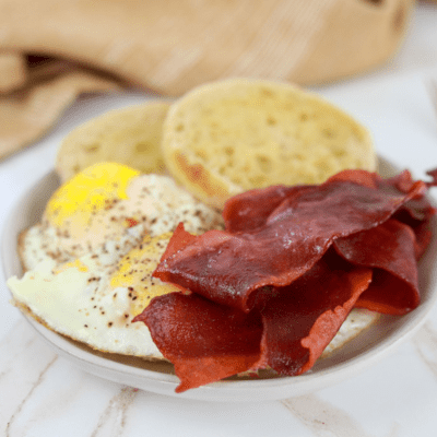 strips of bacon next to a fried egg in a ramekin