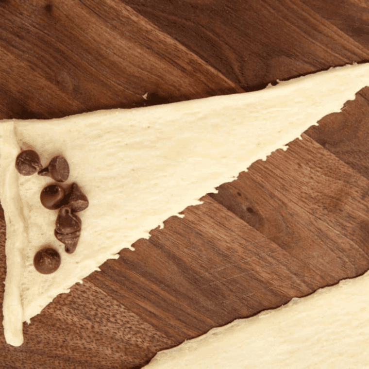 Add chocolate chips to the center of the crescent rolls.