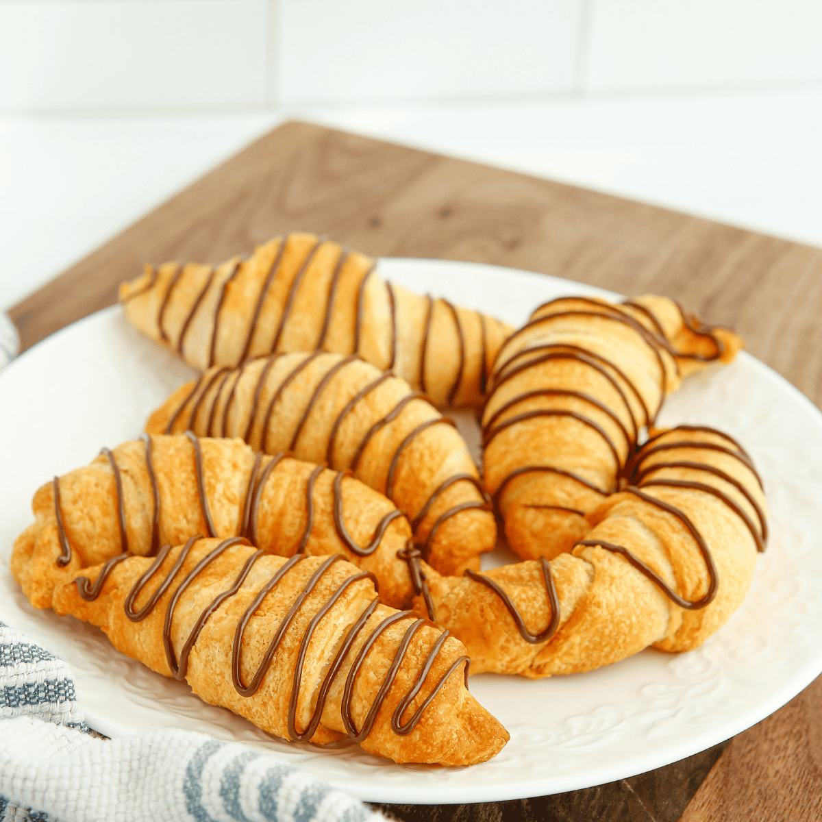 Flaky homemade chocolate turnover drizzled with icing on parchment paper.