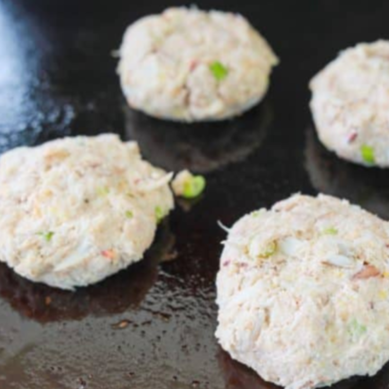 Forming crab cakes with hands before placing them on the Blackstone.