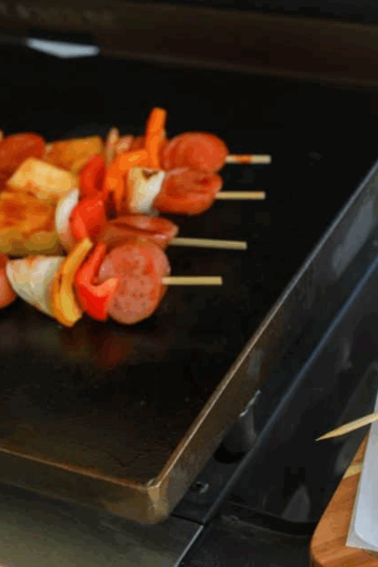 Grilled Hawaiian kielbasa kabobs with pineapple, peppers, and BBQ sauce on a Blackstone griddle.