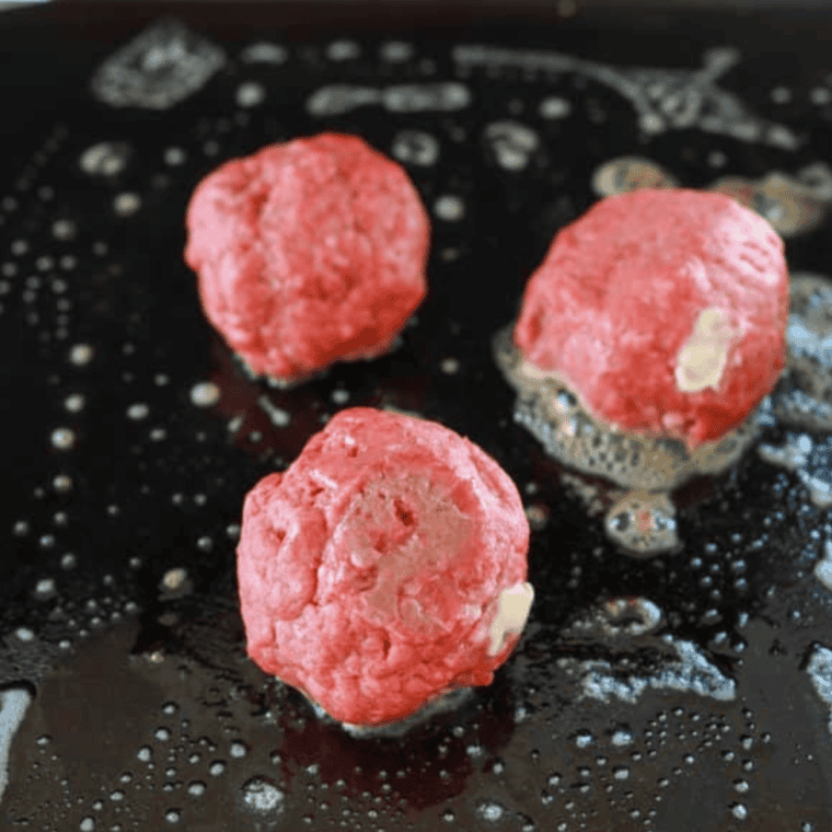 Divide ground beef into balls and prepare griddle with butter.