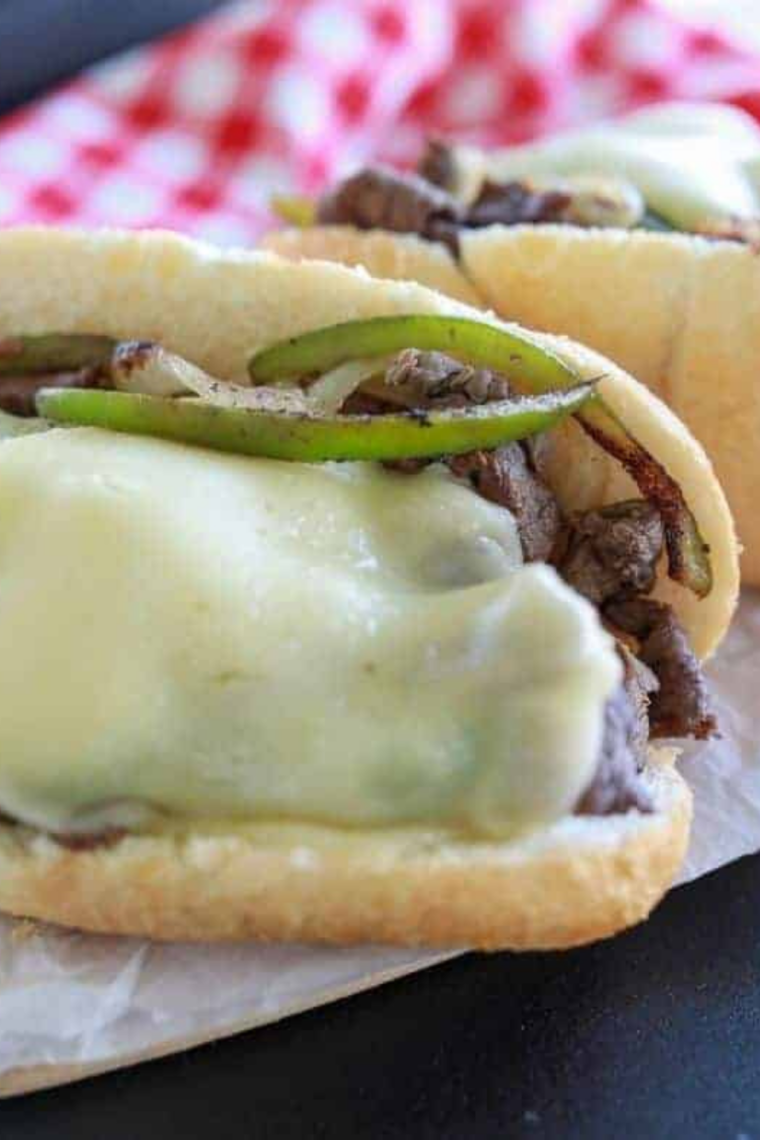 Homemade Philly cheesesteak cooking on a Blackstone griddle with sizzling beef and vegetables.